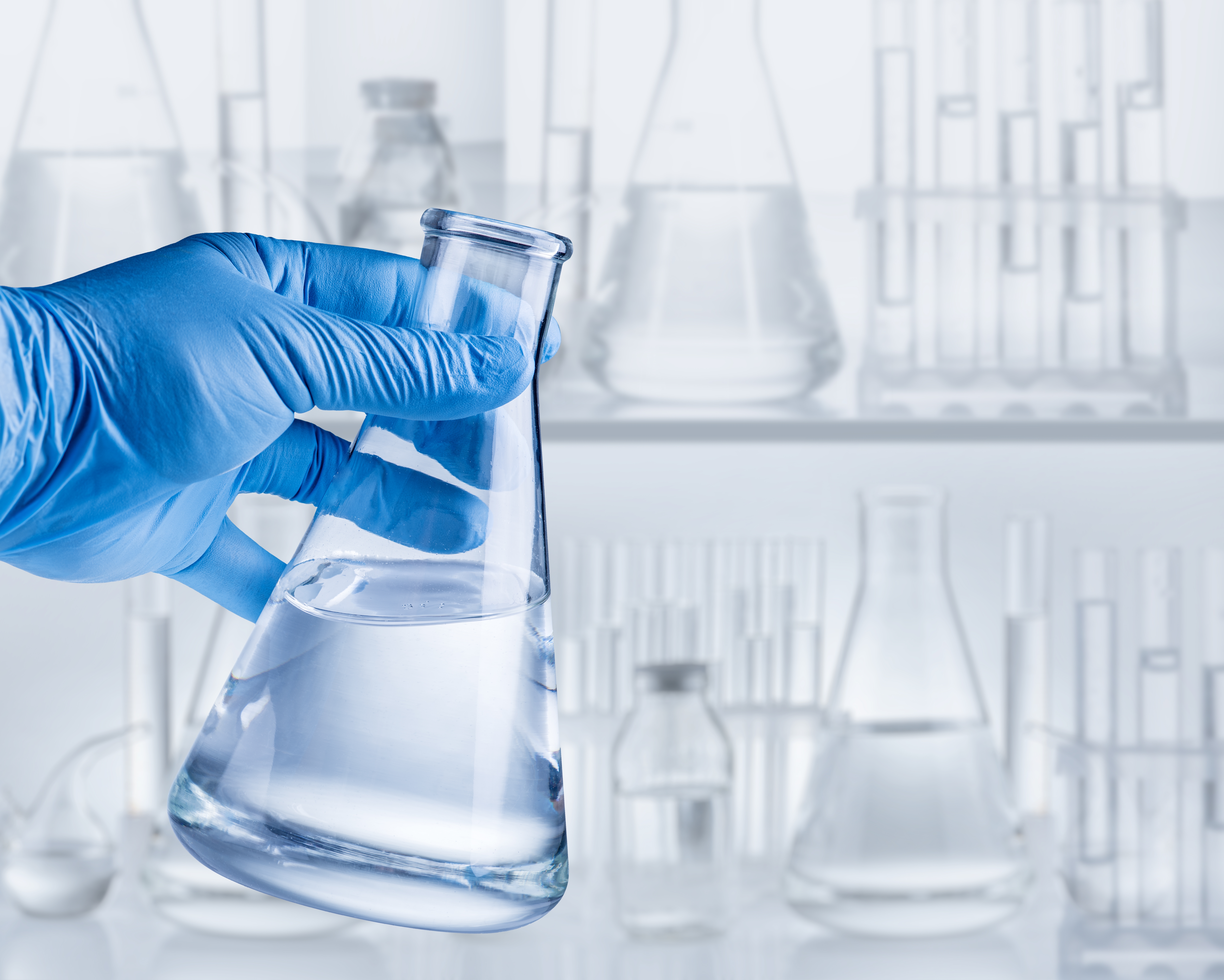 Conical,Flask,In,Hand,In,Blue,Glove,And,Laboratory,Equipment